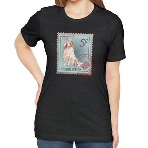 Op de afbeelding: Donkergrijs T-shirt met een postzegelontwerp met een illustratie van een Engelse Setter. De postzegel is lichtblauw met de tekst "5&cent;" en "English Setter". Een rood poststempel is ook zichtbaar.