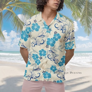 Könnte beinhalten: Ein kurzärmeliges Hemd mit Knöpfen, cremefarbenem Hintergrund und blauem Blumenmuster. Das Hemd hat einen Kragen und eine Knopfleiste vorne. Der Text "Alquimia Designs" ist in der rechten unteren Ecke des Hemdes sichtbar.