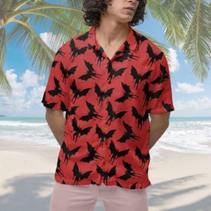 May include: A red short-sleeved button-down shirt with a black bat pattern. The shirt has a relaxed fit and a collar.