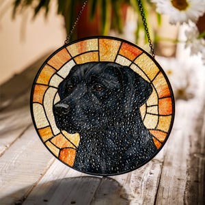 May include: Round stained glass window featuring a black Labrador Retriever. The dog's portrait is set against a background of orange and yellow glass, framed by a black metal border. A decorative chain is attached for hanging.