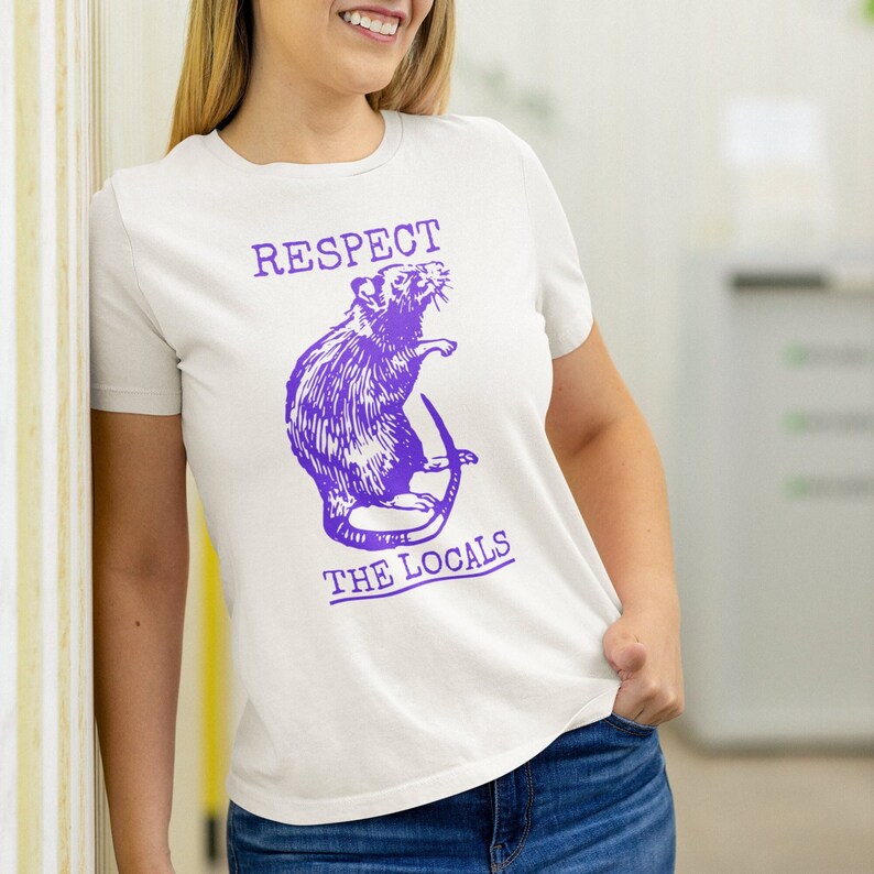 May include: White t-shirt with a purple rat illustration and the text "Respect the Locals".