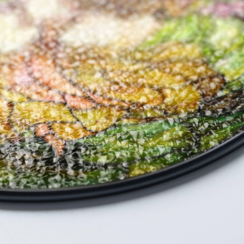 Op de afbeelding: Een rond, decoratief bord met een kleurrijk moza&iuml;ekontwerp. Het bord heeft een getextureerd, glasachtig oppervlak met een zwarte rand.