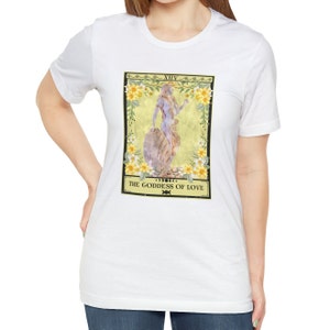 May include: White t-shirt with a graphic of a tarot card depicting a goddess with the text "XIV THE GODDESS OF LOVE"