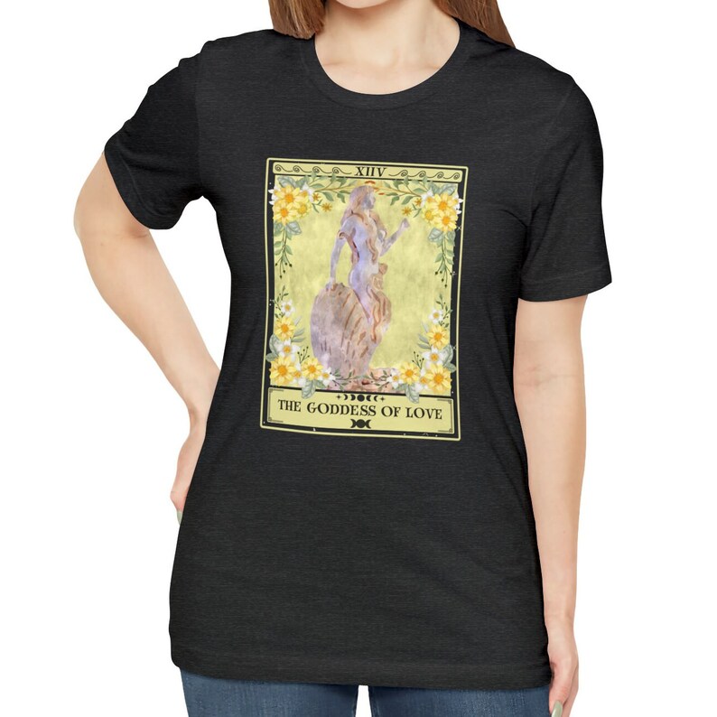 May include: A black t-shirt with a tarot card design featuring a woman standing on a rock with flowers around her. The card reads "XIV THE GODDESS OF LOVE".