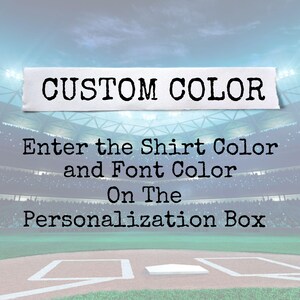 May include: Image with text that reads "CUSTOM COLOR". Below the text, it says "Enter the Shirt Color and Font Color On The Personalization Box". The background is a baseball field.