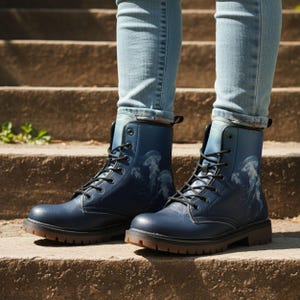 Könnte beinhalten: Marineblaue Kampfstiefel mit einem Quallen-Design. Die Stiefel haben schwarze Schnürsenkel, eine runde Spitze und eine braune Sohle. Die Stiefel werden mit einer blauen Jeans getragen.