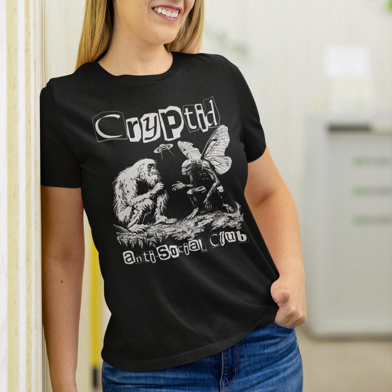 May include: Black t-shirt with a white graphic print of two cryptids, a Bigfoot and a moth, with the text "Cryptid Anti Social Club".