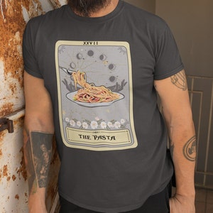May include: A dark gray t-shirt with a tarot card design featuring a plate of pasta with a fork and the text "The Pasta" and "XXVII" on the card.