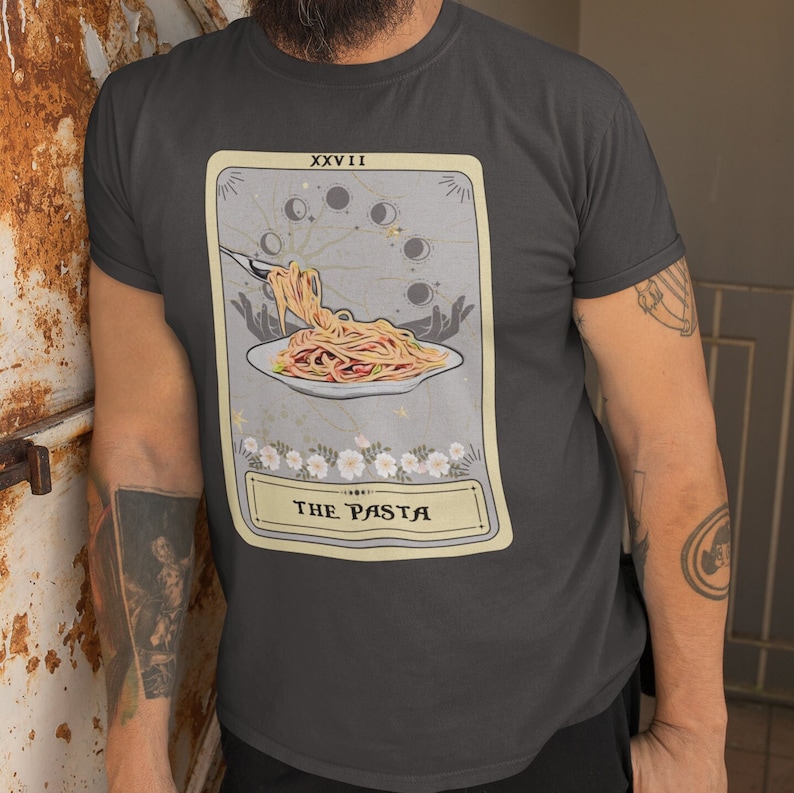 May include: A dark gray t-shirt with a tarot card design featuring a plate of pasta with a fork and the text "The Pasta" and "XXVII" on the card.