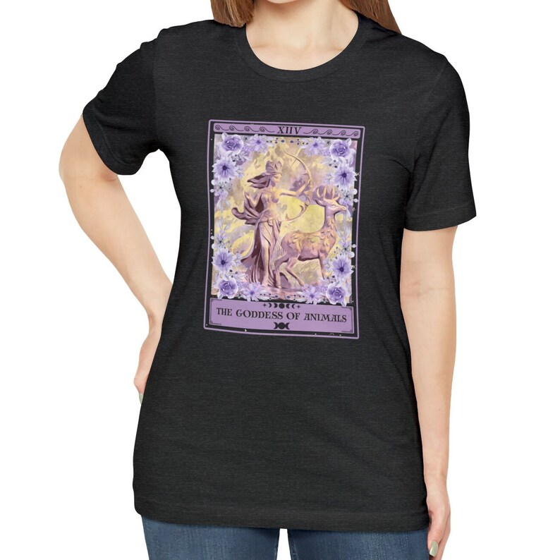 May include: A black t-shirt with a purple and white tarot card design. The card depicts a woman with a bow and arrow, standing next to a deer. The card is labeled "XIV THE GODDESS OF ANIMALS".