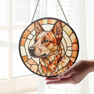 May include: Round stained glass window featuring a dog's portrait in shades of brown, orange, and cream. The dog's head is in profile, with a black border and chain for hanging. The glass is segmented with a stained glass effect.