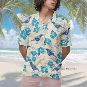 May include: A white short-sleeved button-down shirt with a tropical print featuring blue flowers and black birds. The shirt has a collar and a button-up front.