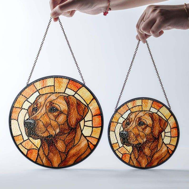 May include: Two round stained glass dog portraits with a brown and orange color scheme. Each piece features a Labrador Retriever's head and shoulders, framed by a black border and a chain for hanging.