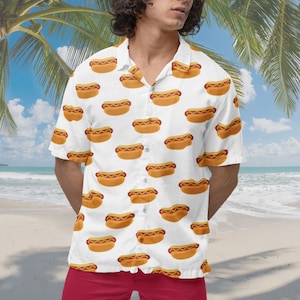 May include: A white short-sleeved button-down shirt with a pattern of yellow hot dogs on a white background.