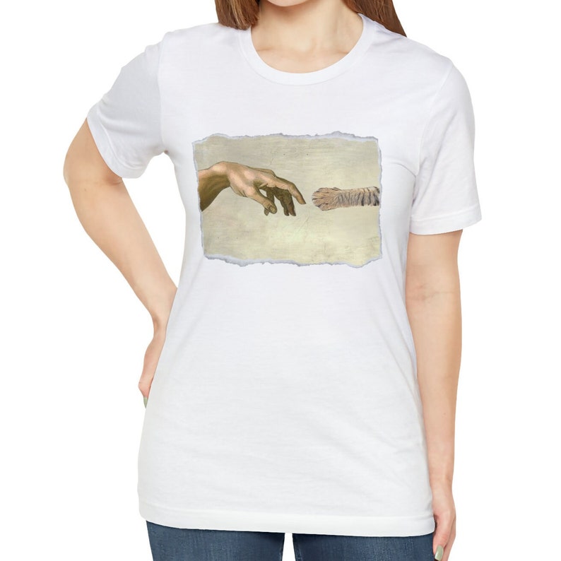 May include: A white t-shirt with a graphic of a tiger paw and a human hand reaching out to touch it, referencing the famous "Creation of Adam" painting.