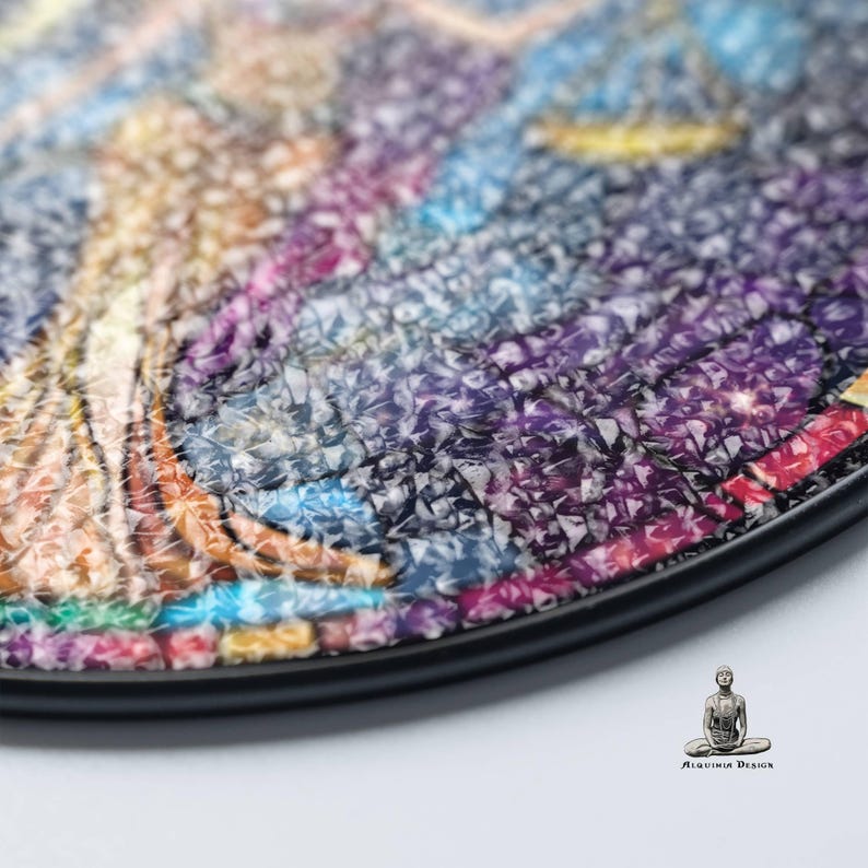 May include: Close-up of a round, colorful mosaic art piece with a black frame. The mosaic is made of small, iridescent tiles that create a textured surface.