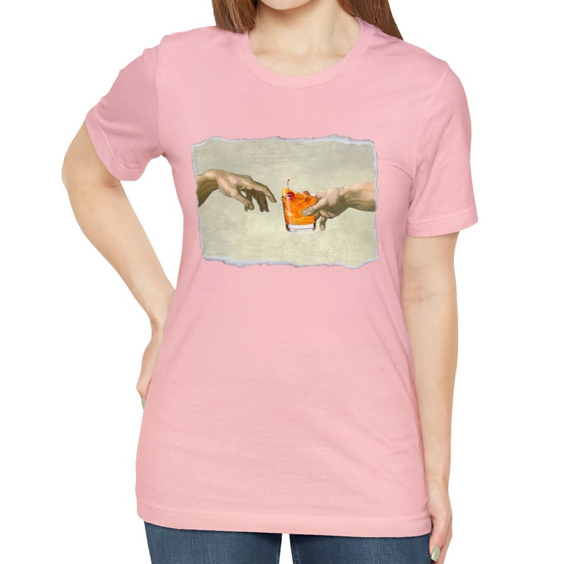 May include: A pink t-shirt with a graphic of the "Creation of Adam" painting, but instead of God touching Adam's finger, they are both reaching for a glass of orange juice with a cherry.
