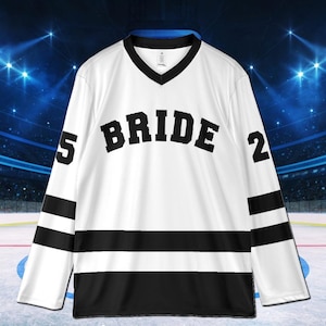 Pu&ograve; includere: Maglia da hockey bianca con dettagli neri. La parola "BRIDE" &egrave; sul petto in lettere nere in grassetto. La maglia ha strisce nere in basso e sulle maniche, con i numeri "5" e "2" sulle maniche.