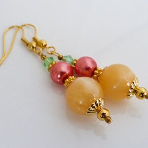 May include: Gold earrings with peach and pink beads and green crystals.