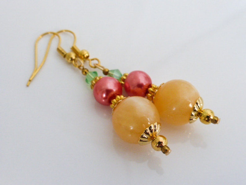 May include: Gold earrings with peach and pink beads and green crystals.