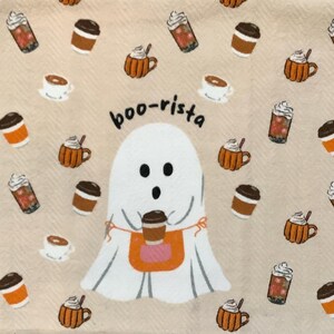 May include: A beige fabric with a repeating pattern of coffee drinks and mugs. A cartoon ghost wearing an apron that says "boo-rista" is holding a coffee cup. The design includes orange, brown, white, and beige colors.