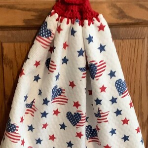 May include: Red, white, and blue kitchen towel with a crocheted loop and button. The towel features a pattern of stars and hearts with the American flag design.