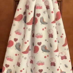 May include: Red crocheted dish towel holder with a button and a white dish towel with a pattern of red and gray birds, hearts, and clouds.