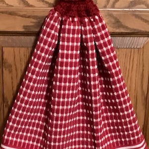 May include: Red and white checkered kitchen towel with a red crocheted loop and a white button.