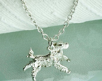 May include: A silver necklace with a detailed, textured pendant shaped like a dog. The dog is in a running pose with its head turned to the side.