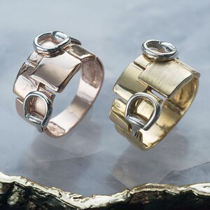 Könnte beinhalten: Zwei goldene Ringe mit einem einzigartigen Design, das einen Akzent aus weißem Metall aufweist. Der Ring links ist aus Roségold und der Ring rechts aus Gelbgold.