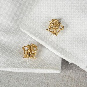 May include: A pair of gold cufflinks featuring a detailed dragon design.