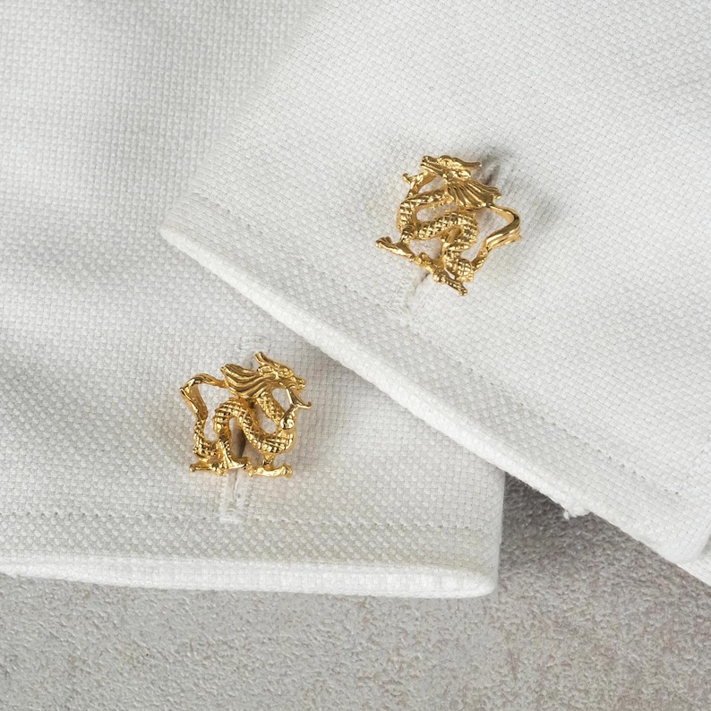May include: A pair of gold cufflinks featuring a detailed dragon design.