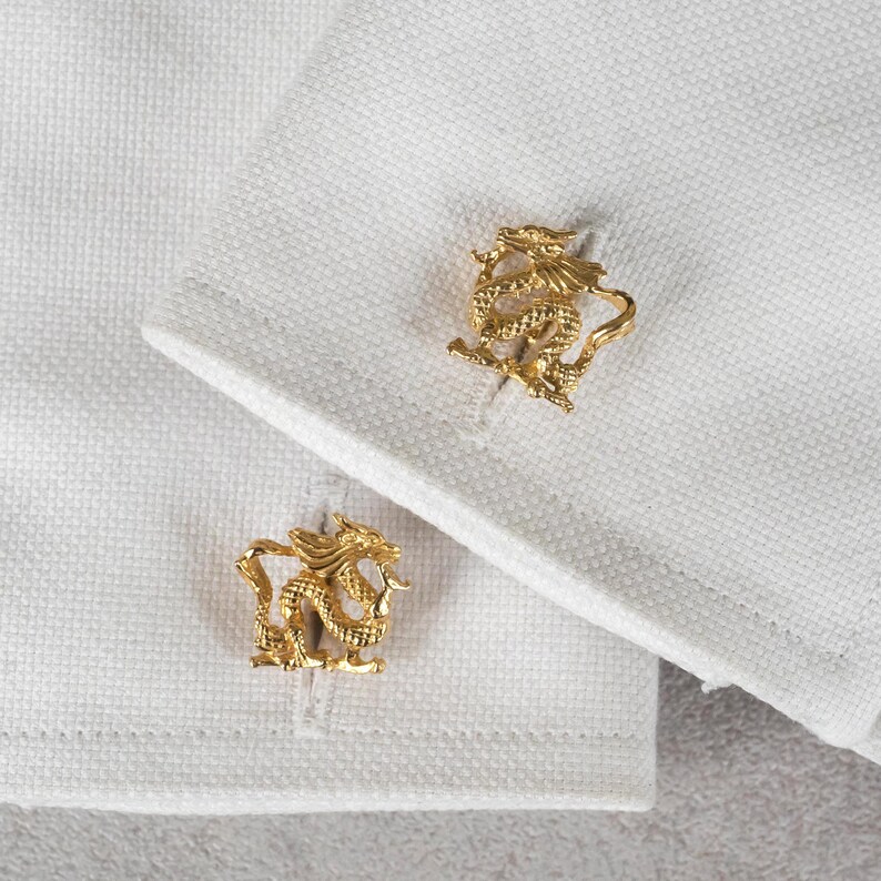 May include: A pair of gold cufflinks featuring a detailed dragon design.