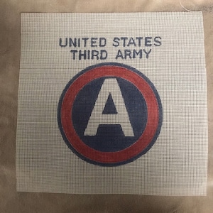 May include: Square canvas with the text "UNITED STATES THIRD ARMY" above a circular emblem. The emblem features a large white "A" inside a blue circle, bordered by a red ring. The canvas has a grid-like texture.