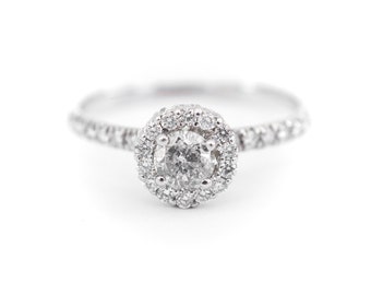 May include: A silver ring with a large round diamond surrounded by a halo of smaller diamonds. The band is also set with smaller diamonds.