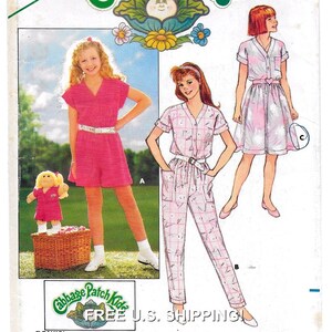 May include: A sewing pattern for a Cabbage Patch Kids doll and two children's outfits. The doll is wearing a pink dress. The first outfit is a pink jumpsuit with short sleeves. The second outfit is a pink and white checked jumpsuit with long sleeves. The third outfit is a pink and white dress with short sleeves.