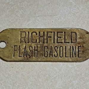 May include: A brass tag with the words "Richfield Flash Gasoline" embossed on it. The tag has a small hole at the top left corner.