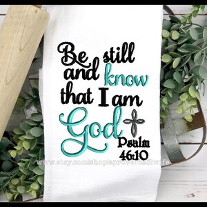 May include: White kitchen towel with teal blue embroidery that reads "Be still and know that I am God" with a small cross and the text "Psalm 46:10" below.
