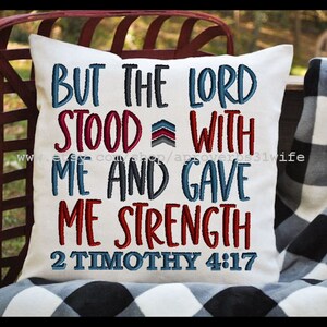 May include: White pillow with red, blue, and gray embroidered text that reads "But the Lord stood with me and gave me strength 2 Timothy 4:17".