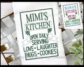 May include: A white kitchen towel with green embroidery that reads "Mimi's Kitchen Open Daily Serving Love Laughter Hugs Cookies".