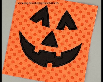 May include: Orange fabric with a black embroidered jack-o'-lantern face. The fabric has a white polka dot pattern.