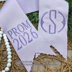 May include: A white ceramic mug with a black handle and the text "But First, Coffee" in a bold, black font. The mug is set against a blurred background, suggesting a cozy setting. The mug appears to be approximately 4 inches tall.