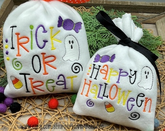 Puede incluir: Dos bolsas blancas con cordón con temática de Halloween. Una bolsa dice "Trick or Treat" con un fantasma y un caramelo. La otra dice "Happy Halloween" con un fantasma y un caramelo. Ambas bolsas tienen letras moradas, naranjas y amarillas.