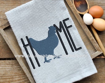 May include: A gray kitchen towel with the word "HOME" embroidered in black with a black silhouette of a chicken in the middle of the word.