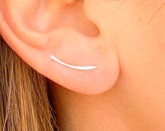 May include: A pair of silver ear cuffs, each with a curved, thin bar that extends from the earlobe.