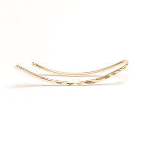 May include: A gold hammered wire ear cuff. The wire is bent into a curved shape.