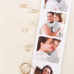 May include: A collection of gold and silver earrings in various styles, including hoops, ear cuffs, and wire designs. A photo strip of a mother and child hugging is next to the earrings. The background is a light, neutral color.