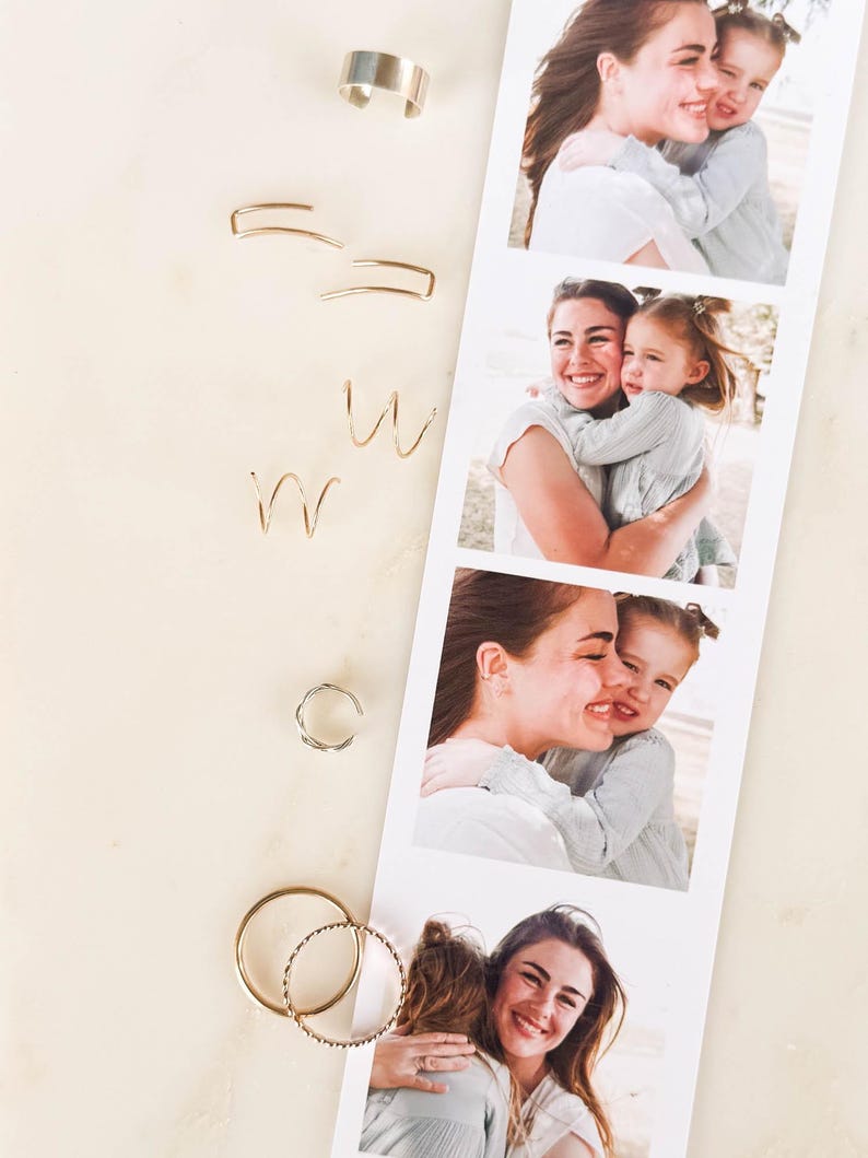 May include: A collection of gold and silver earrings in various styles, including hoops, ear cuffs, and wire designs. A photo strip of a mother and child hugging is next to the earrings. The background is a light, neutral color.