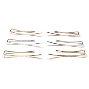 May include: Six ear cuffs in three different styles. Two are gold, two are silver, and two are rose gold. Each cuff is a simple, curved shape.