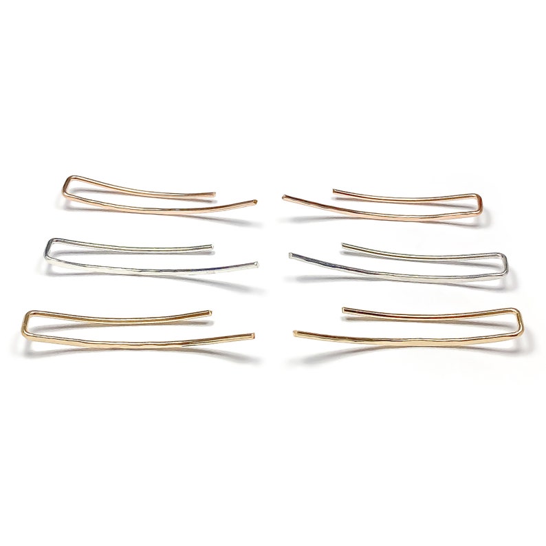 May include: Six ear cuffs in three different styles. Two are gold, two are silver, and two are rose gold. Each cuff is a simple, curved shape.